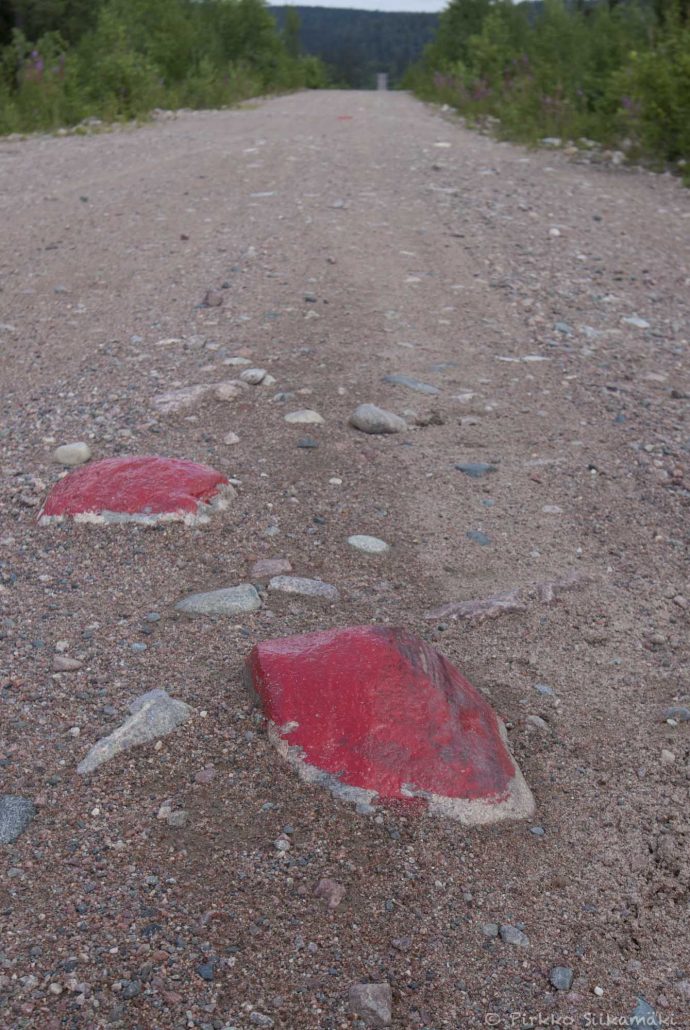 Punaiseksi maalatut kivet puiston tiellä